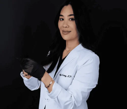 A female doctor in a white lab coat holding a syringe, ready to perform a facial injection.